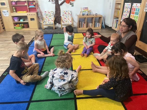 Circle time with a teacher and children on a colorful mat