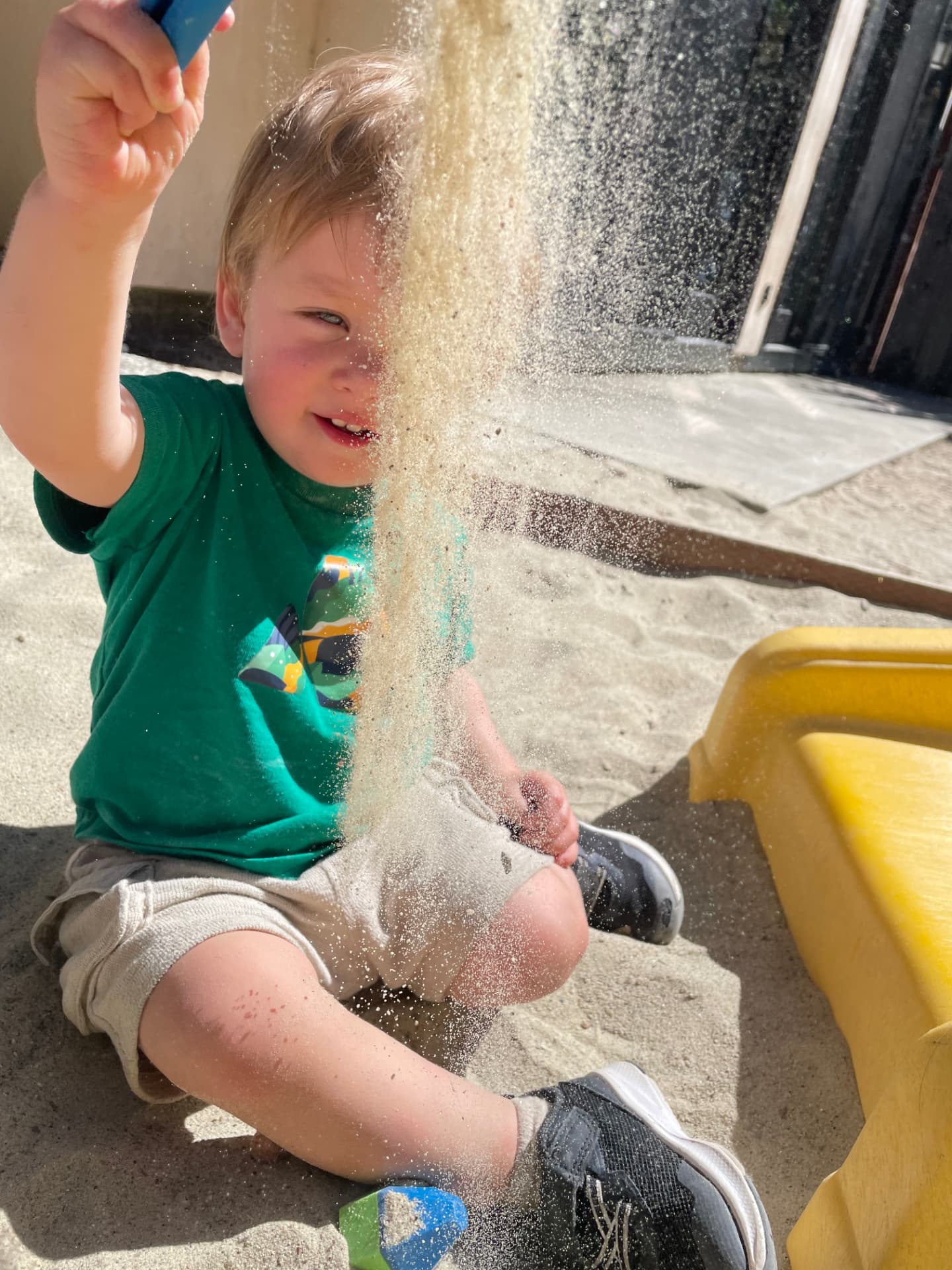 Toddler joyfully playing with sand in the outdoor yard