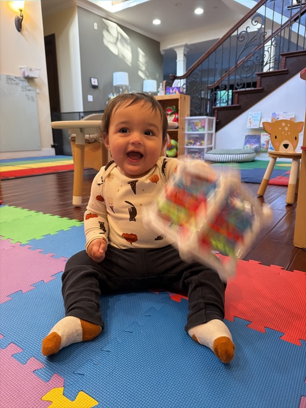 A happy baby playing with an activity cube on the play mat