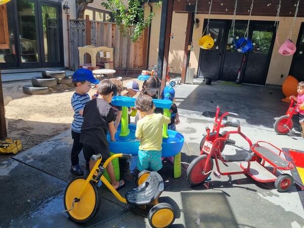 Children gathered around the outdoor water table