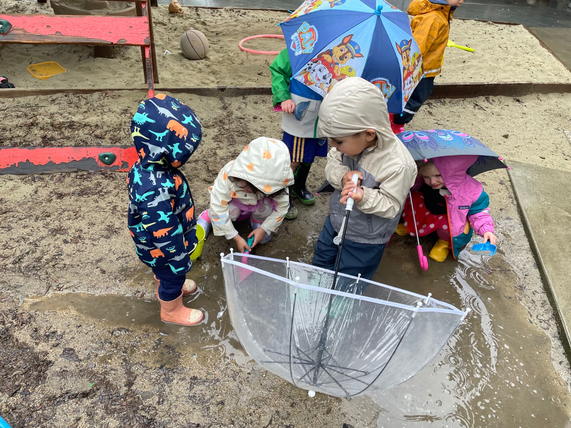 Children playing with umbrellas in the rain in the outdoor yard