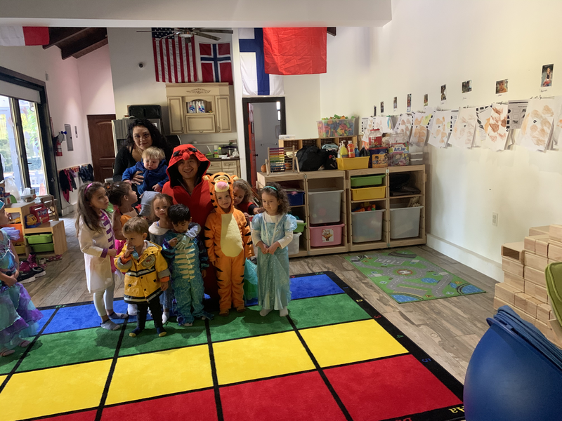 Children in Halloween costumes with their teachers in the classroom