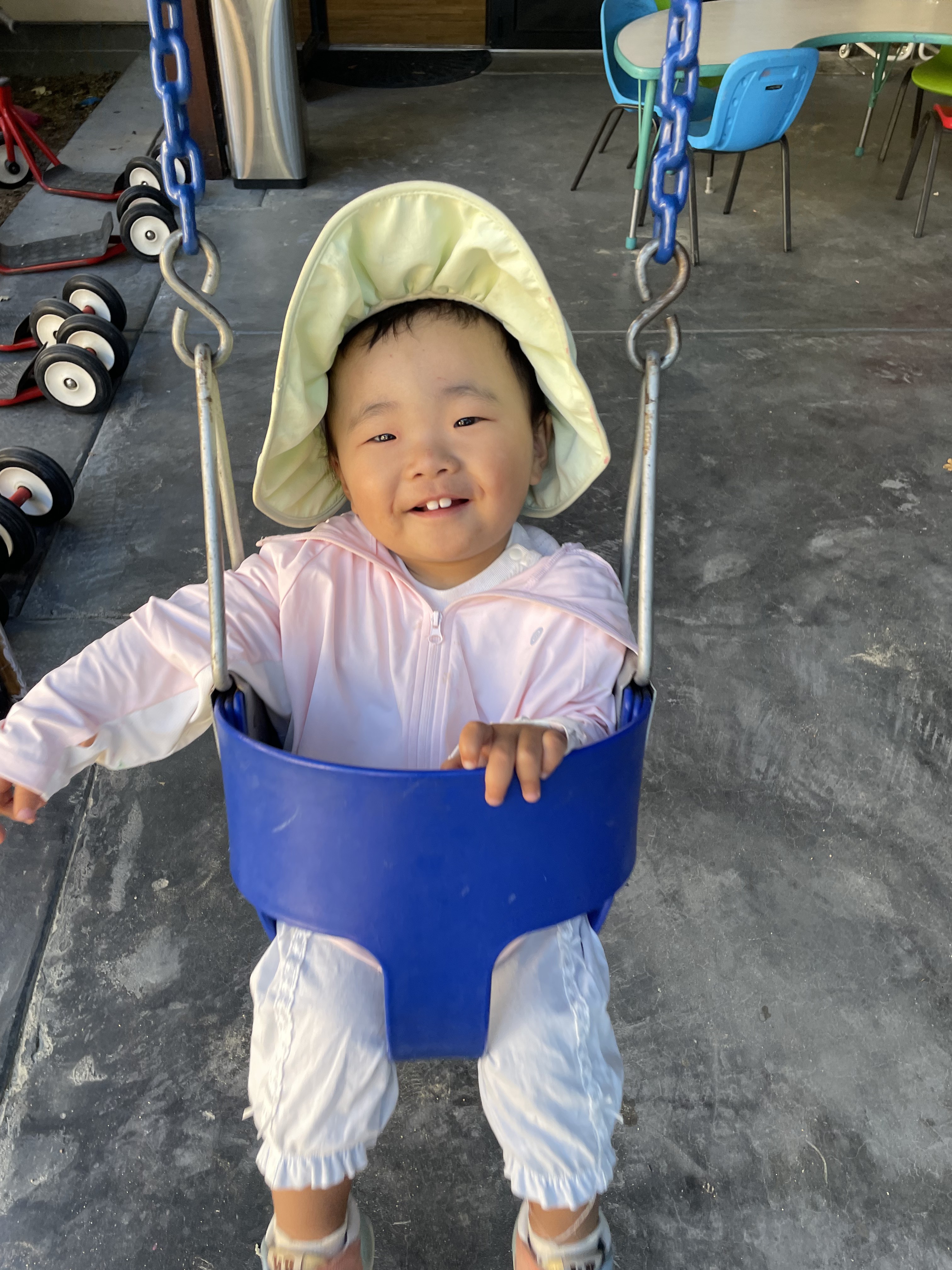 A smiling toddler enjoying the outdoor swing