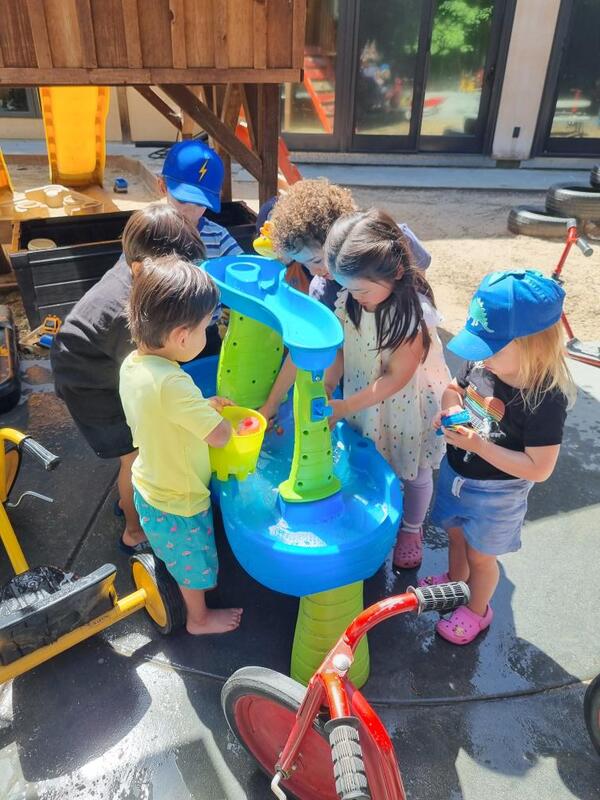 Friends exploring water play together in the sunshine