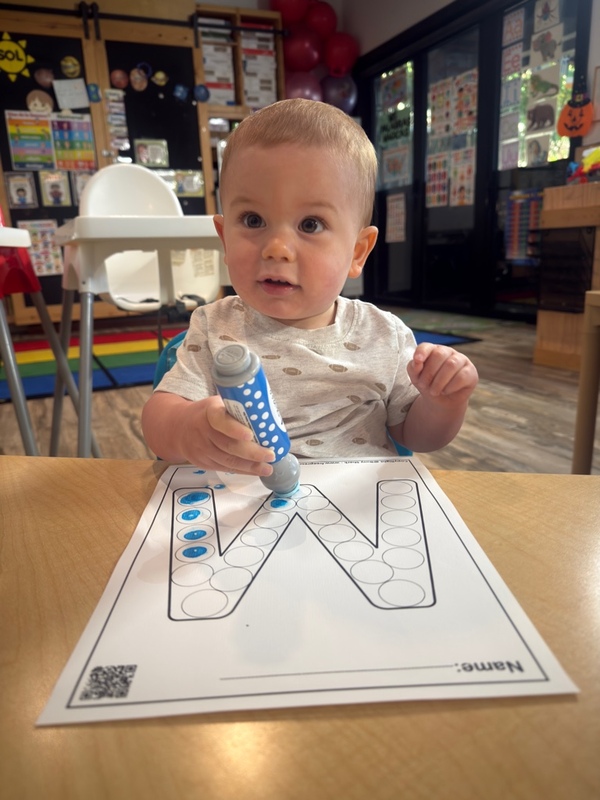 Toddler practicing early letters with a dot marker