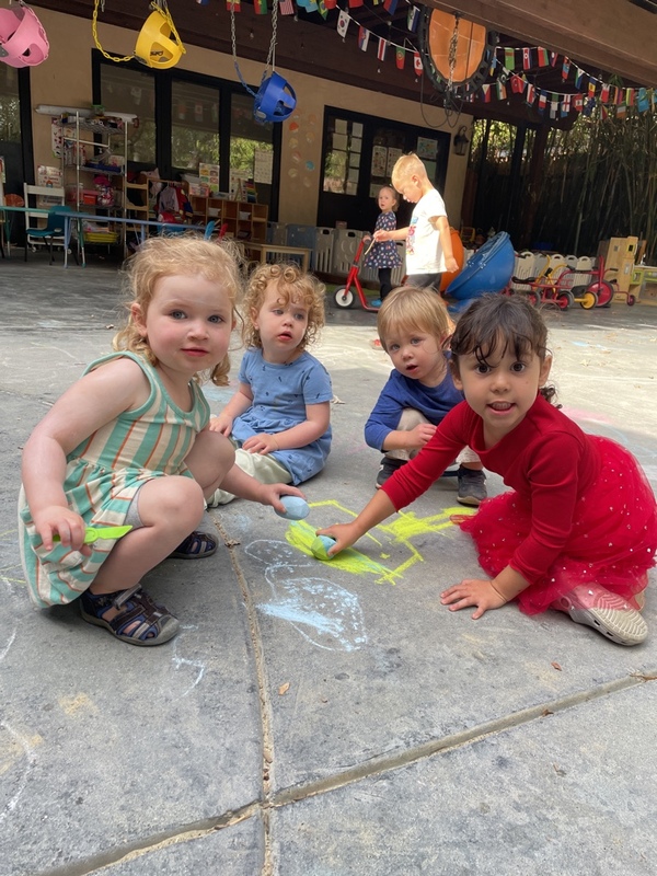 Children creating chalk drawings together outdoors