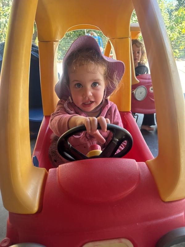 A child enjoying pretend driving in a playground car