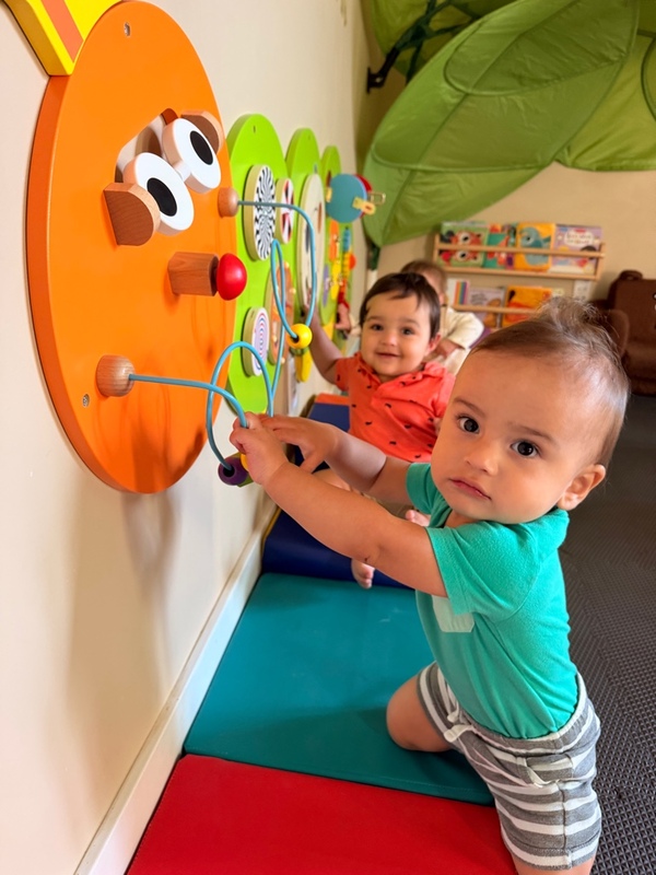 Babies exploring the caterpillar activity wall in the infant room
