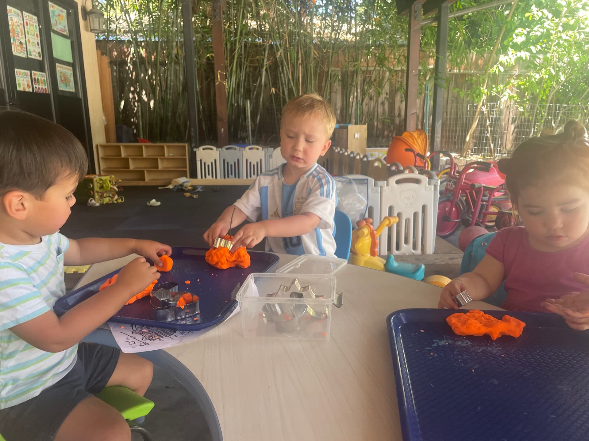 Children shaping play dough with cookie cutters outdoors