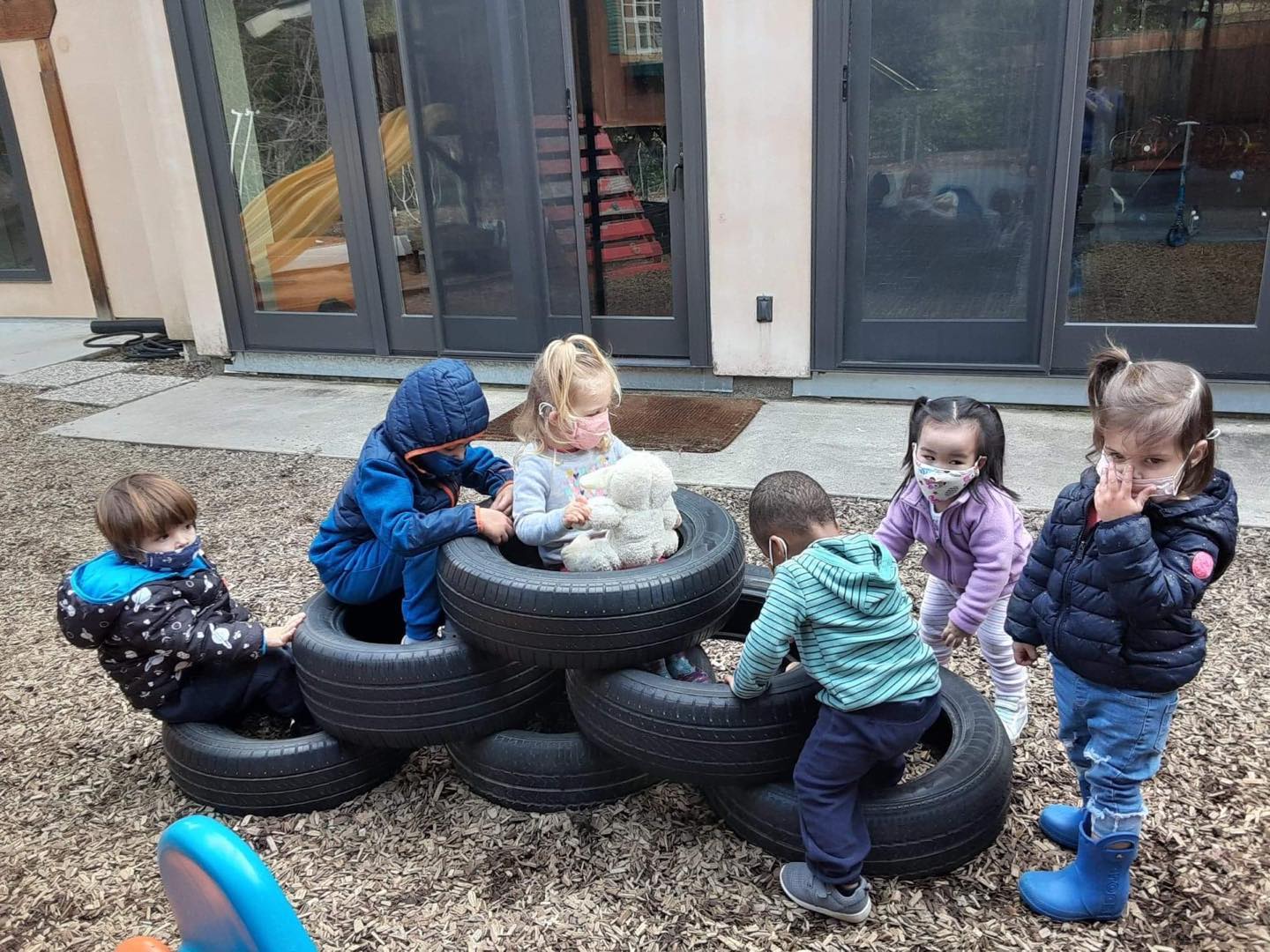 Toddlers climbing and playing on stacked tires in the yard