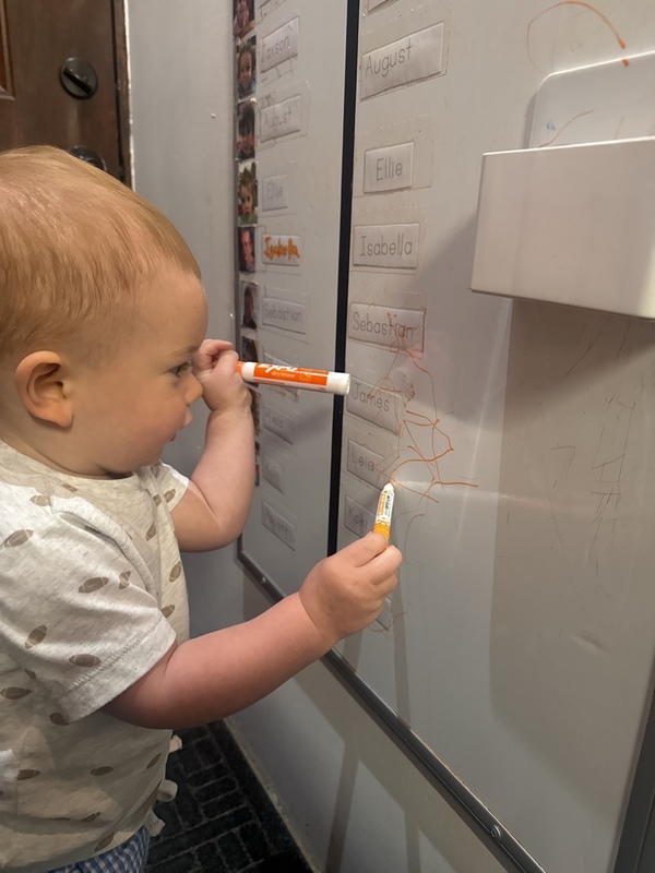A toddler practicing name recognition at the classroom sign-in board